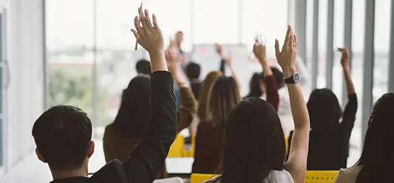 La photo représente plusieurs personnes levant la main en signe d’approbation.