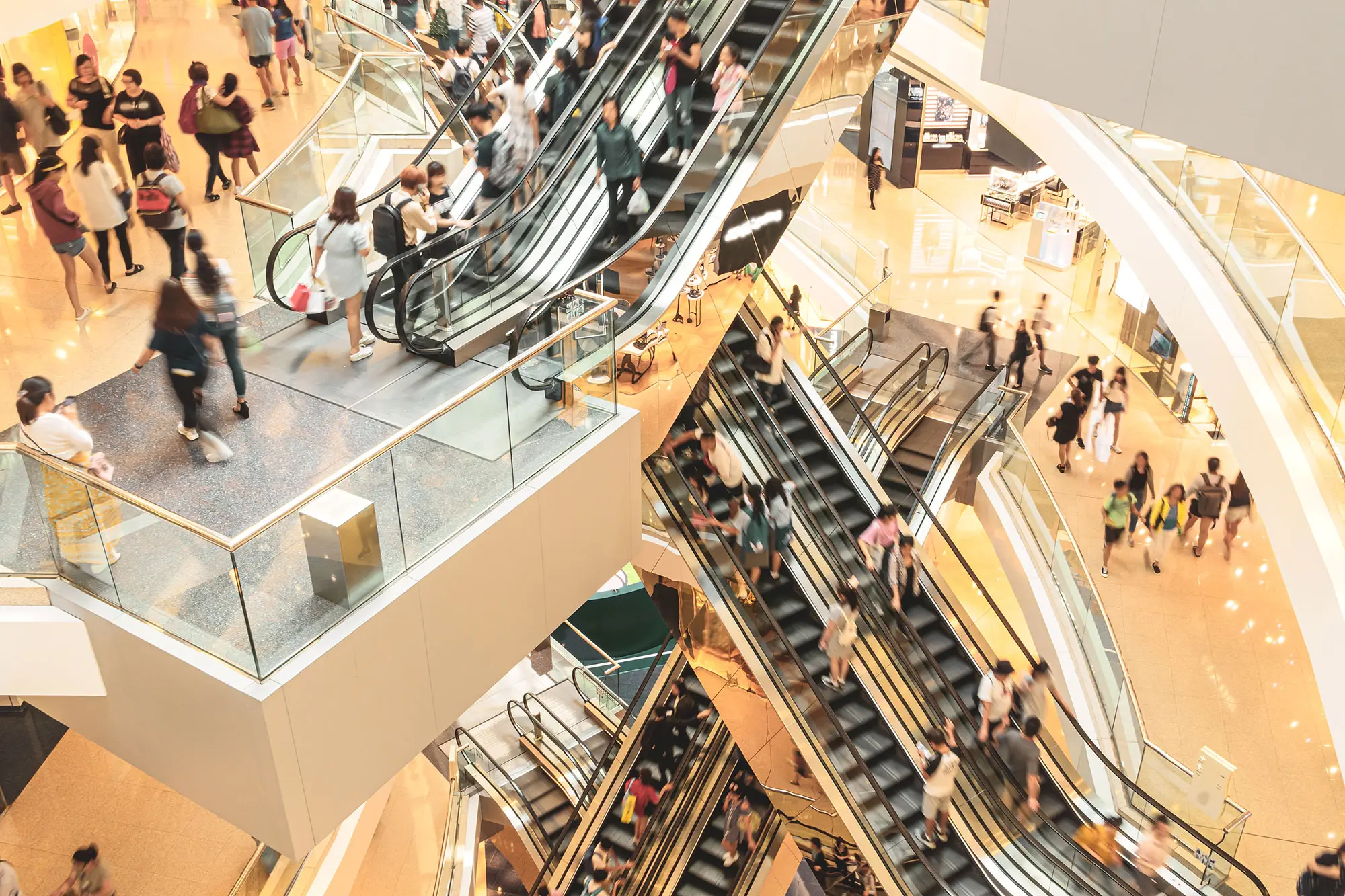 Rolltreppen führen über mehrere Stockwerke. Viele Menschen bewegen sich darauf.
