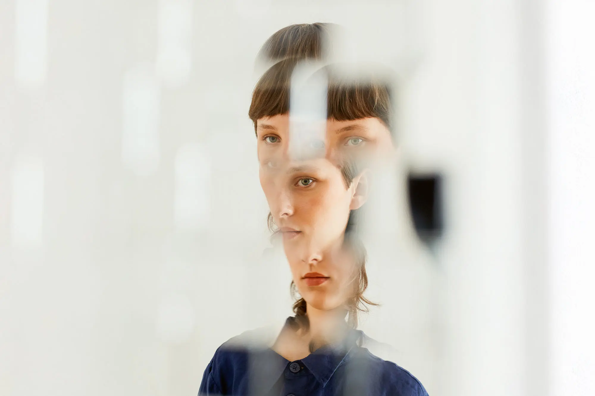 The distorted face of a young woman split into four sections.