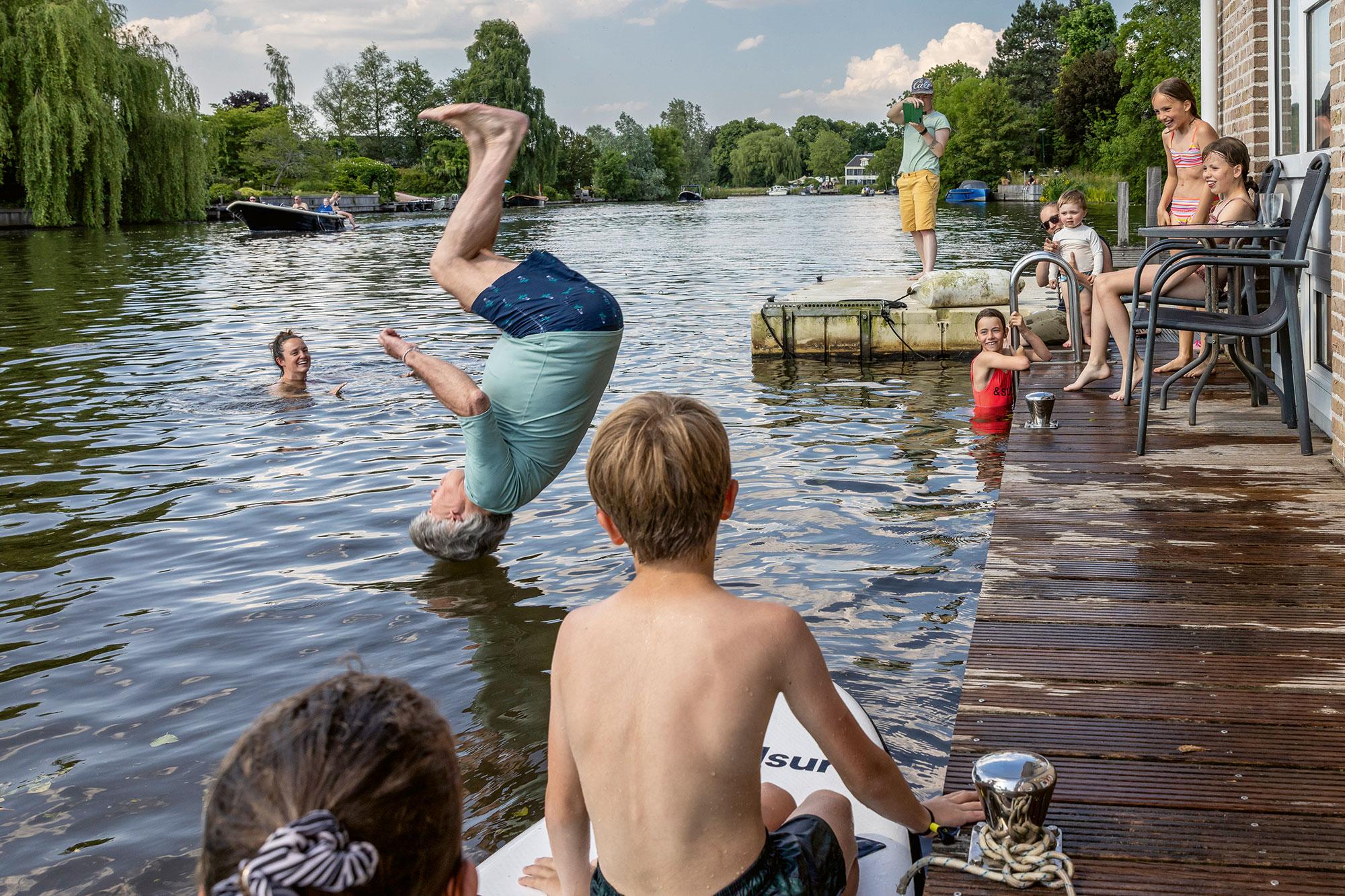 A 71-year-old man somersaults from his houseboat into the water.