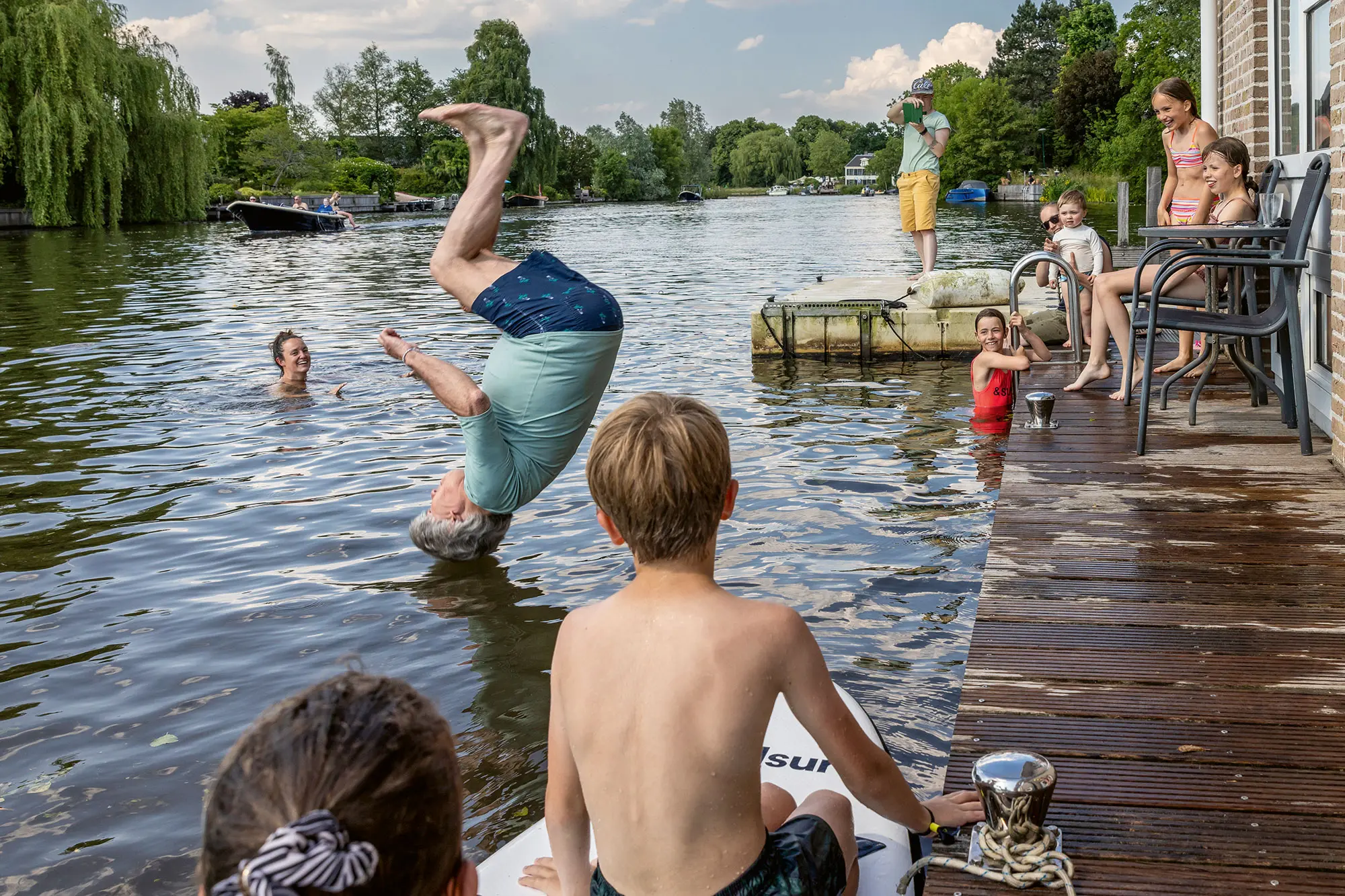 A 71-year-old man somersaults from his houseboat into the water.