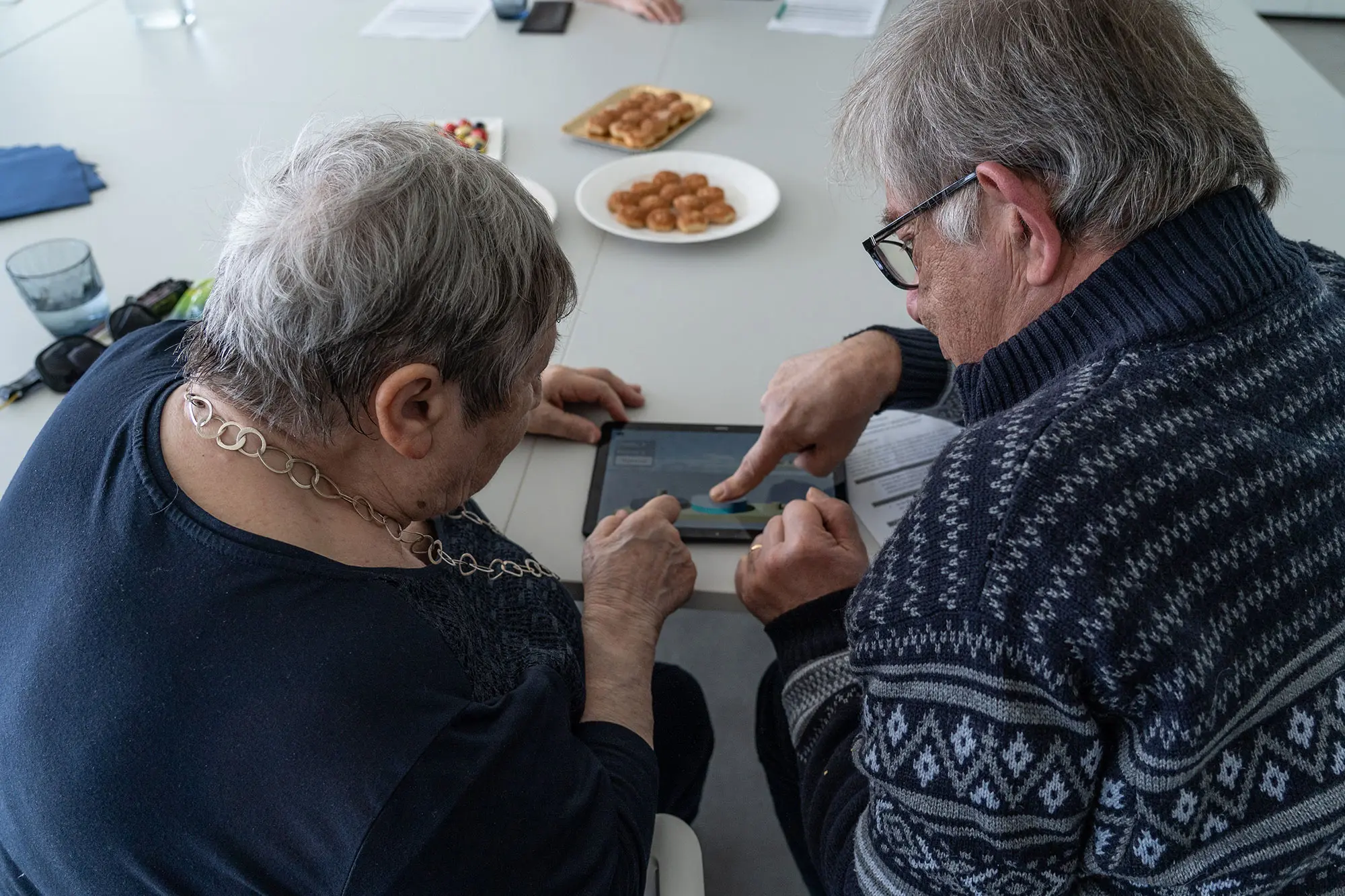 Zwei ältere Personen nutzen gemeinsam ein Tablet.