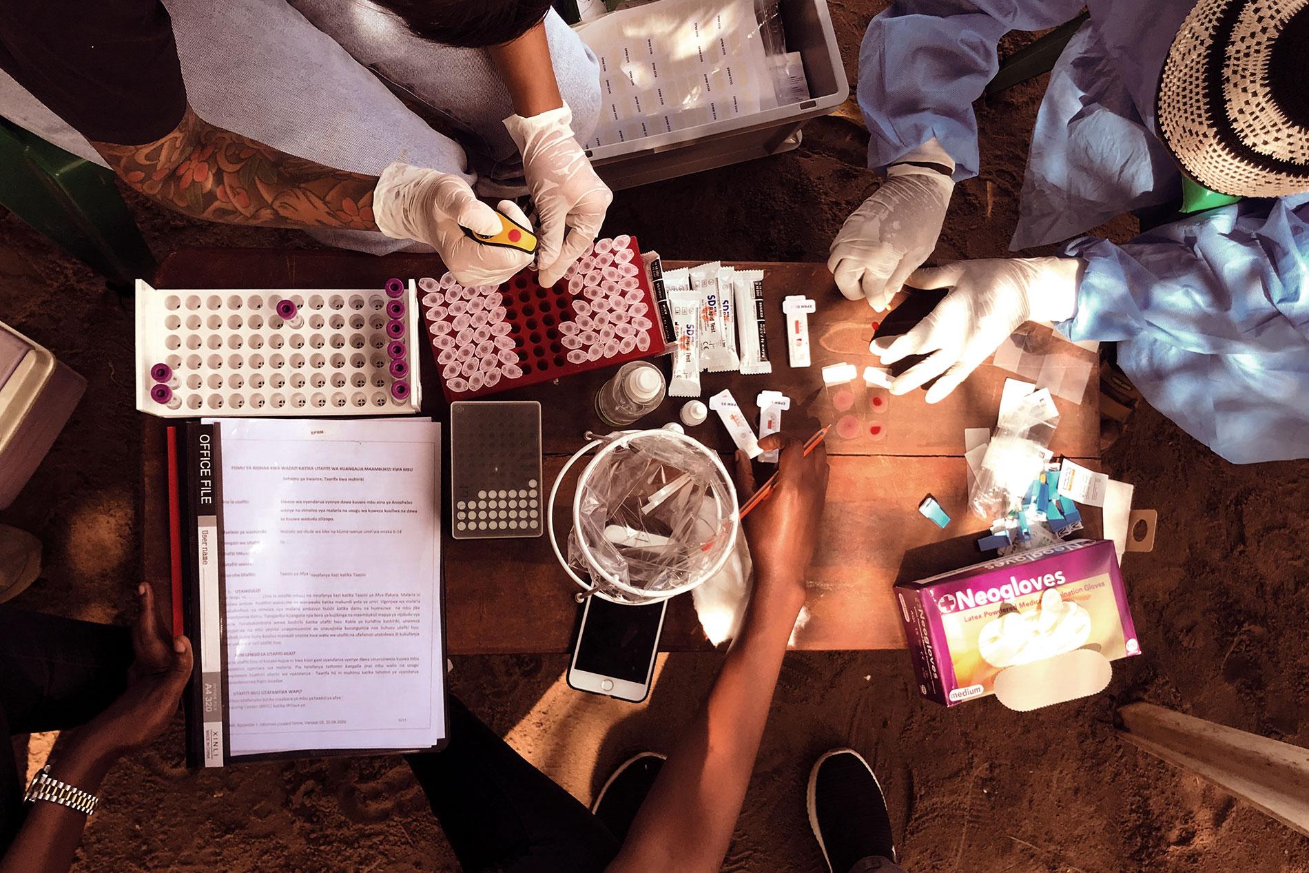 Ein Team von Forschenden, medizinischem und technischem Personal aus der Schweiz und aus Tansania bereitet Malaria-Schnelltests und Blutproben für die Diagnose der Stadien des Malariaparasiten Plasmodium falciparum vor.