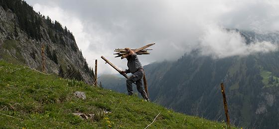 Dieses Bild zeigt einen Landwirt, der seine Alpwiesen für die Sommersaison vorbereitet.